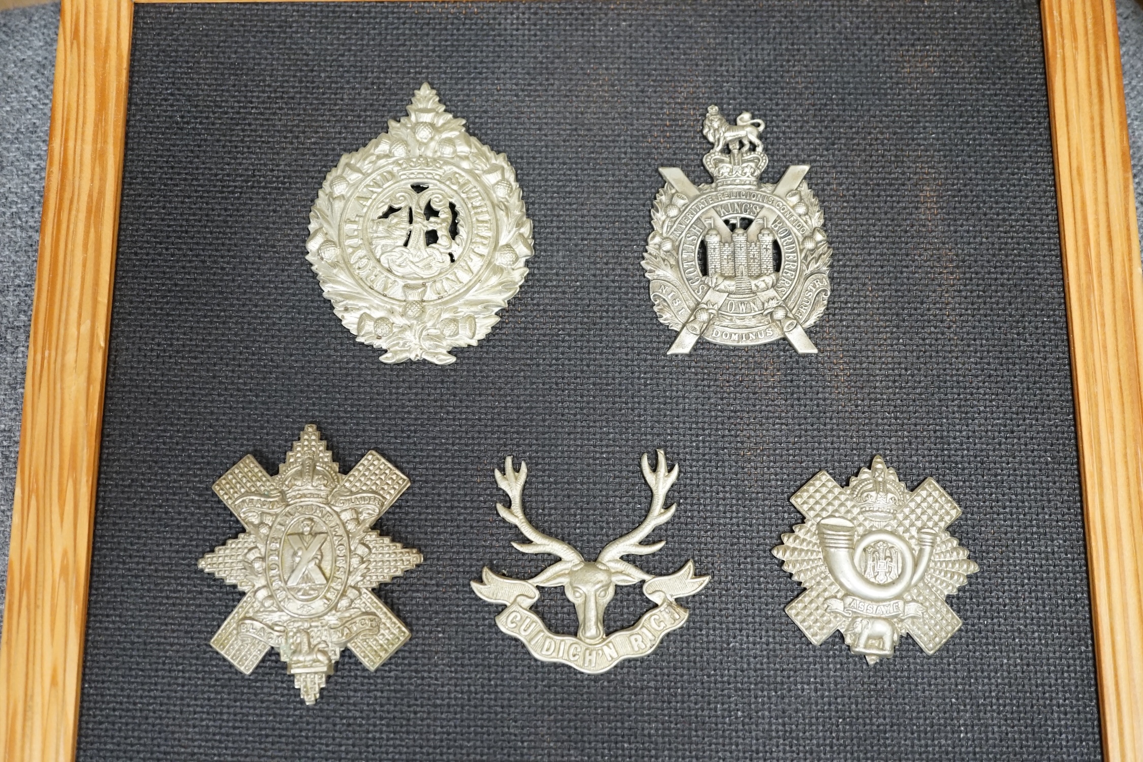 Ten military cap and Glengarry badges mounted on a board including; The King’s Own Scottish Borderers, the Argyle and Sutherland Regiment, the Royal Scots, the Gordon Highlanders, The Queen’s Own Cameron Highlanders, etc